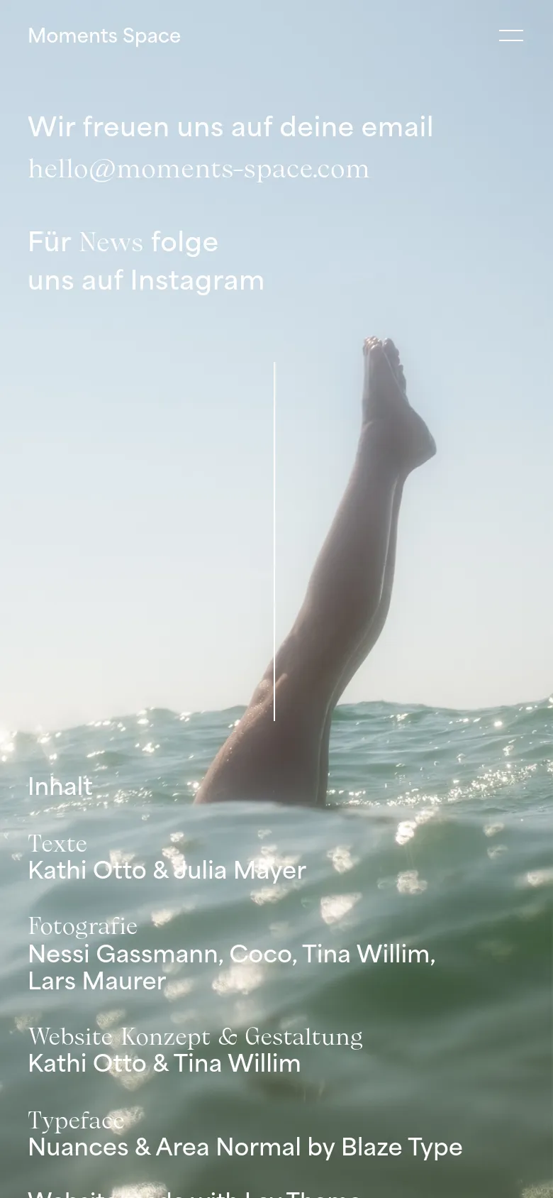 The mobile version maintains the full-screen ocean hero image with the person's legs as the central focus. The text layout is vertically stacked, with the contact information at the top, followed by the image, and the credits section at the bottom. A simplified hamburger menu icon is visible in the top right corner.