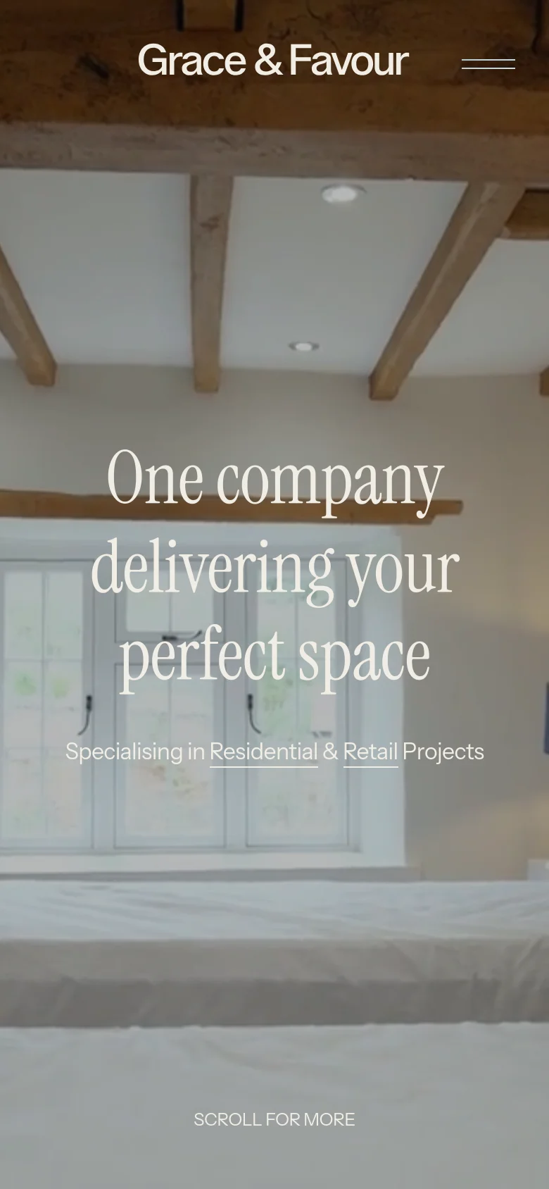 The mobile version presents a vertically oriented hero image of a bright interior with wooden beams and a window. The headline 'One company delivering your perfect space' is stacked centrally in white serif font, followed by the subheadline and a 'SCROLL FOR MORE' prompt at the bottom. The navigation is condensed into a hamburger menu icon at the top right.
