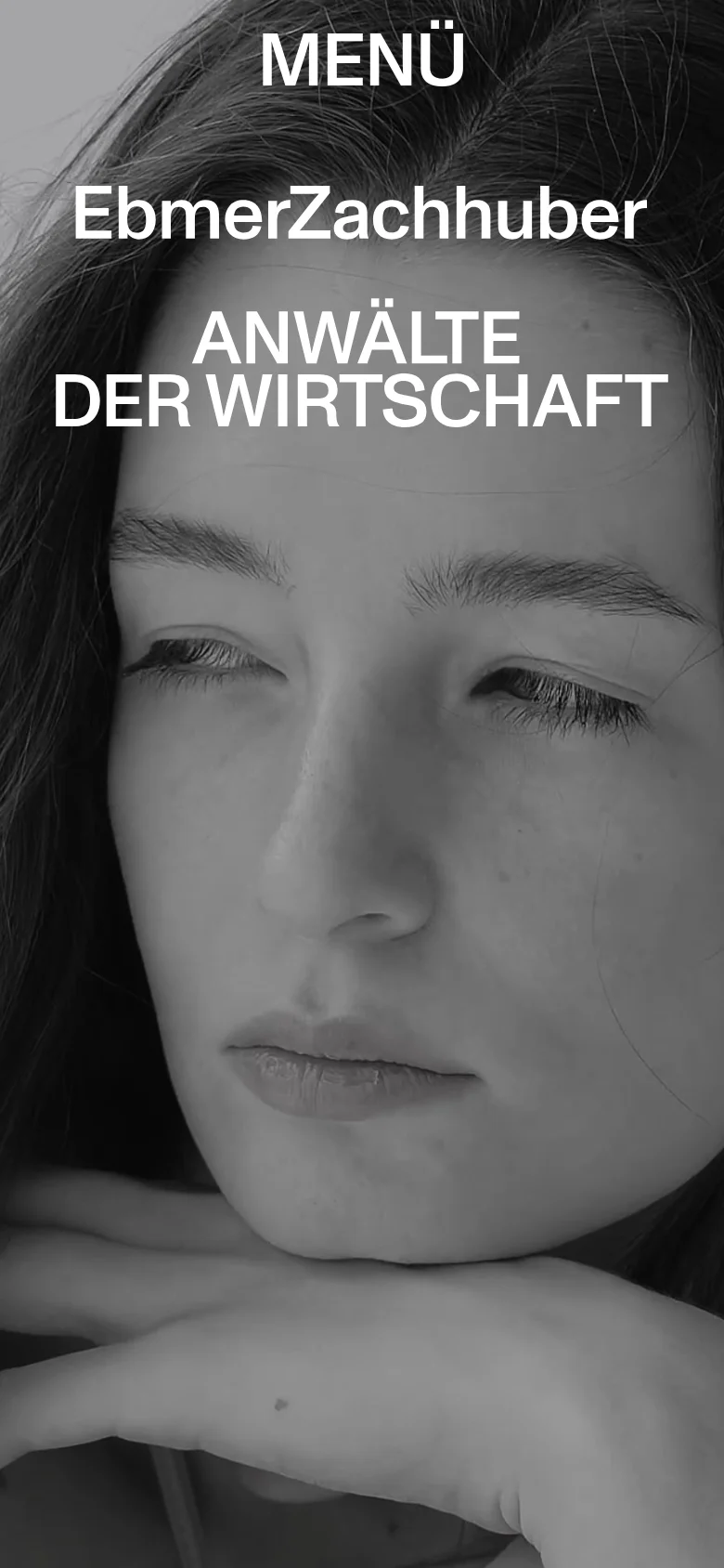 EbmerZachhuber mobile homepage with a stacked layout and a large close-up grayscale portrait as the hero background. The brand name and headline are centered in bold white typography above a prominent MENÜ button.