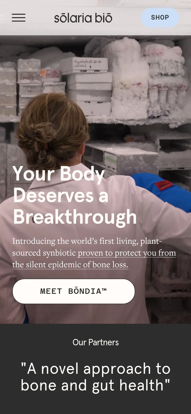 The mobile version shows a vertical layout with a hero image of a scientist in a lab setting looking at frozen samples. The headline 'Your Body Deserves a Breakthrough' is overlaid on the image above a white 'MEET BŌNDIA™' button. A hamburger menu icon and 'SHOP' button are visible in the header.