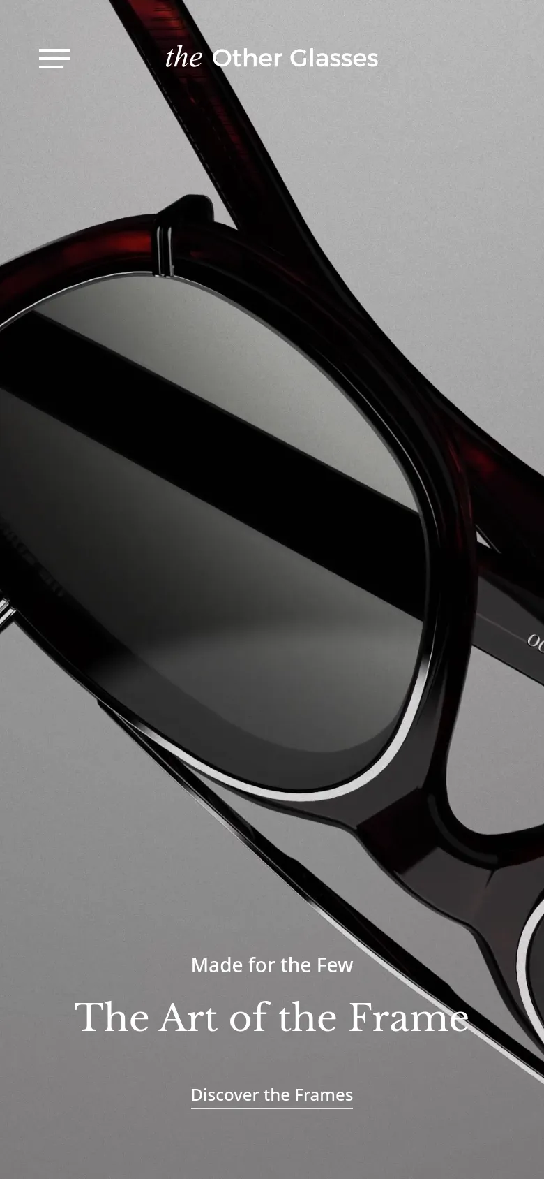 The mobile version uses a simplified layout with a hamburger menu icon on the left and the brand logo centered at the top. The hero section features a close-up, angled shot of dark red eyewear, with the headline 'The Art of the Frame' and a 'Discover the Frames' link positioned at the bottom.