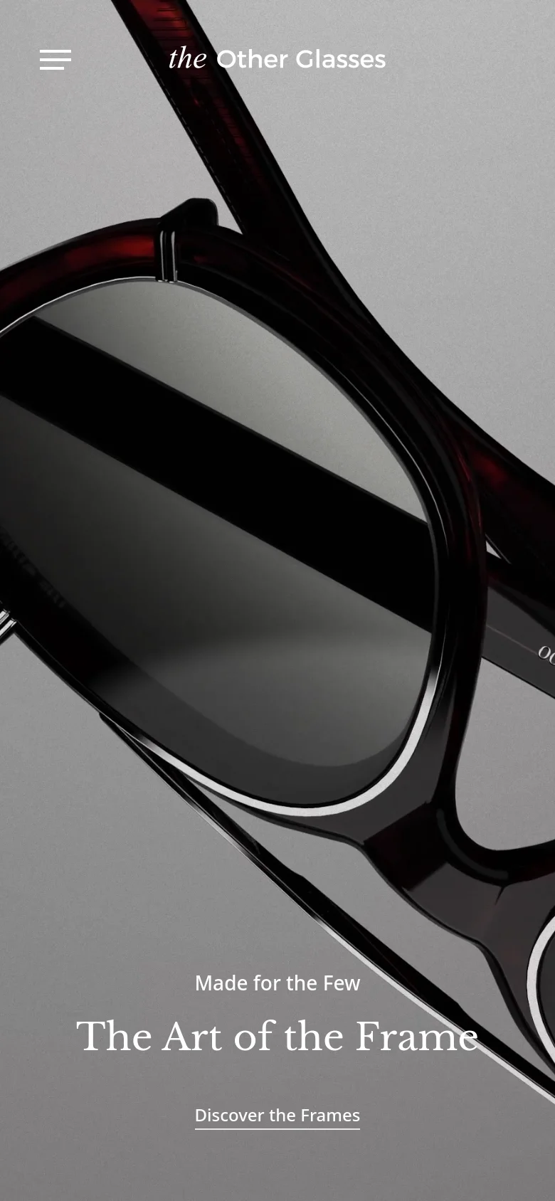 The mobile version uses a simplified layout with a hamburger menu icon on the left and the brand logo centered at the top. The hero section features a close-up, angled shot of dark red eyewear, with the headline 'The Art of the Frame' and a 'Discover the Frames' link positioned at the bottom.