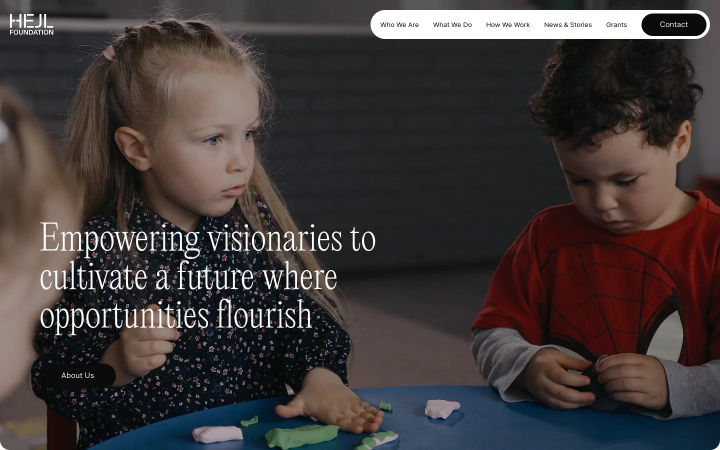 The desktop homepage features a large hero image of two children playing with clay, overlaid with the headline 'Empowering visionaries to cultivate a future where opportunities flourish' and an 'About Us' button. A white navigation bar at the top includes the Hejl Foundation logo and links for Who We Are, What We Do, How We Work, News & Stories, Grants, and a Contact button. The layout is clean with a high-contrast white text on a dark photographic background.