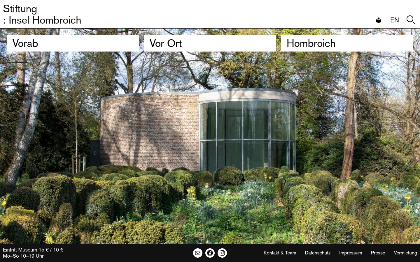 The desktop homepage features a minimalist white header with the title 'Stiftung : Insel Hombroich' and navigation links for 'Vorab', 'Vor Ort', and 'Hombroich' overlaid on a large hero image. The hero image shows a modern brick and glass building nestled among lush green bushes and tall trees. A dark footer contains museum entry information, social media icons, and site links.
