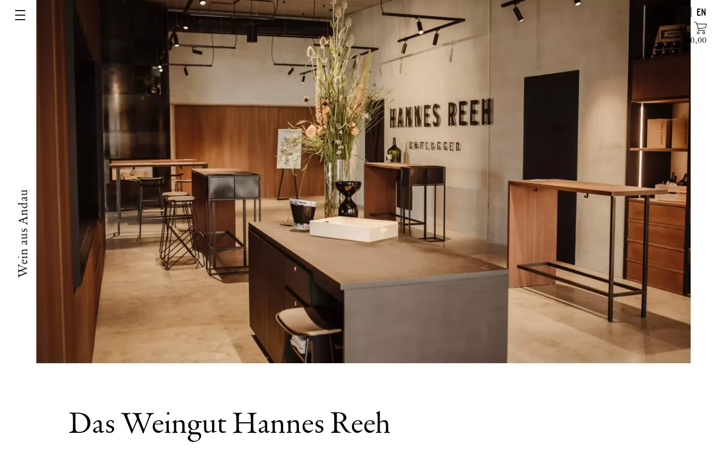 The desktop page features a large hero image of a modern, minimalist winery tasting room with wooden counters and industrial lighting. Below the image, the headline 'Das Weingut Hannes Reeh' is displayed in a large serif font against a white background, followed by text describing tours and tastings. A navigation menu is visible at the top with a hamburger icon, language selector, user icon, and shopping cart.
