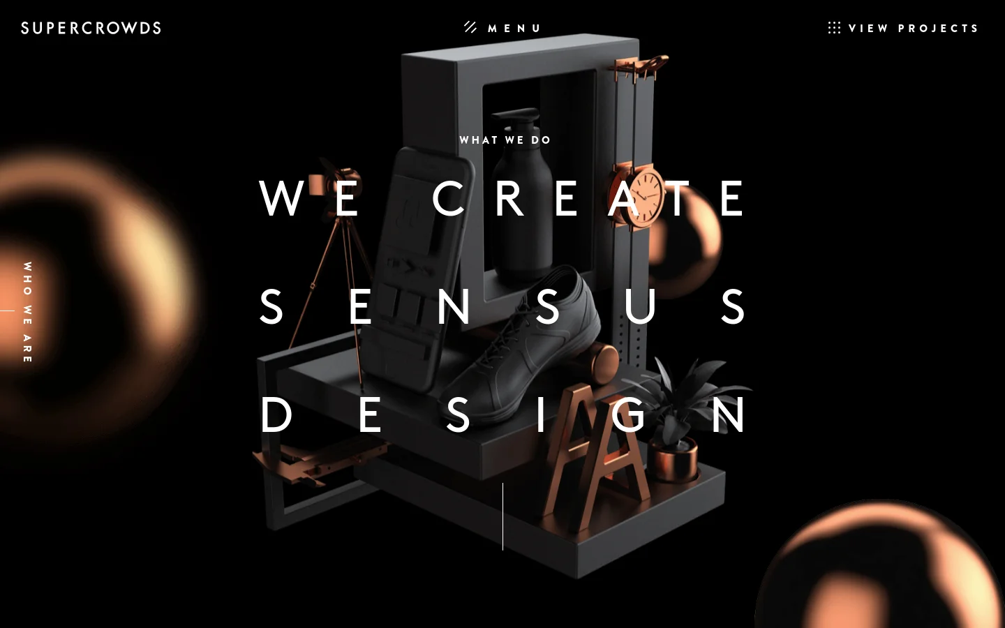 The desktop page features a dark, minimalist aesthetic with a large hero image of 3D rendered objects like a shoe, a bottle, and a clock arranged on geometric blocks. Large white sans-serif typography reads 'WE CREATE SENSUS DESIGN' over the central imagery, with a navigation menu at the top containing 'SUPER CROWDS', 'MENU', and 'VIEW PROJECTS'.