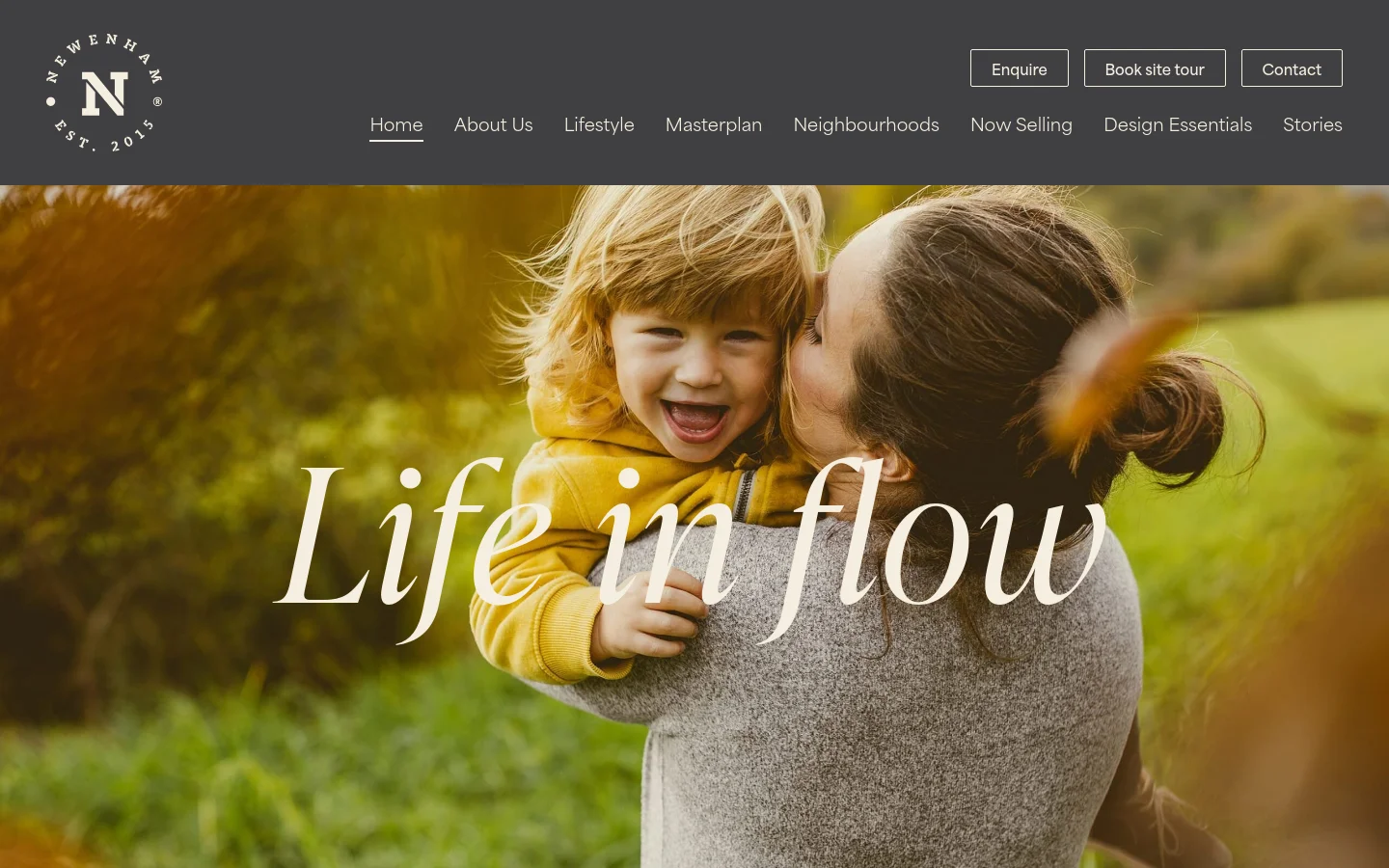 The desktop homepage features a dark grey header with the Newenham logo on the left and navigation links including Home, About Us, and Lifestyle. A large hero image shows a smiling child being held by a woman in a natural, sunlit outdoor setting with the large white text 'Life in flow' overlaid. Primary call-to-action buttons for Enquire, Book site tour, and Contact are positioned in the top right.