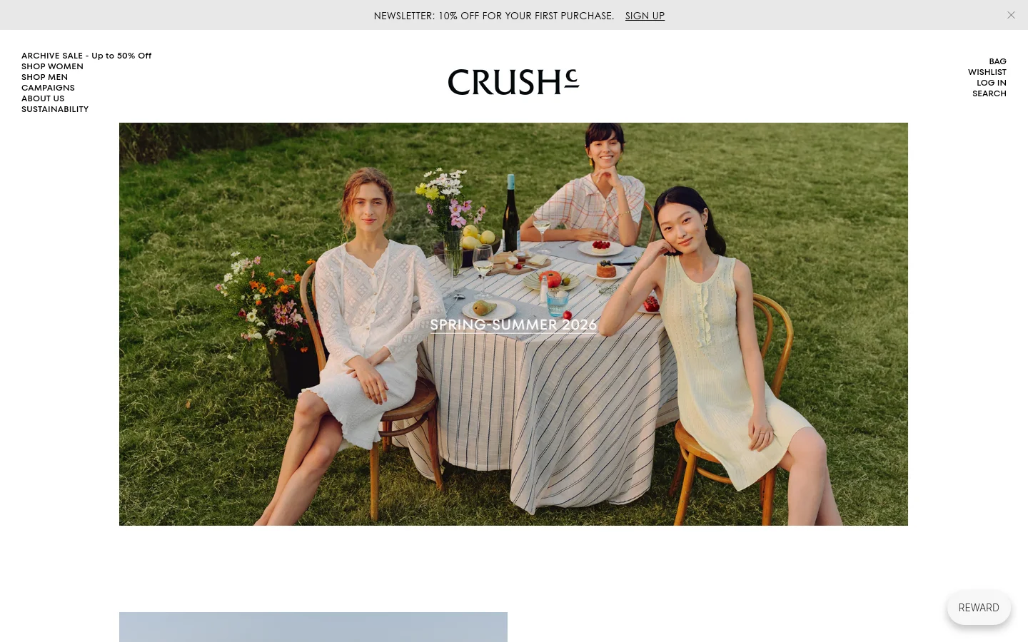 The desktop homepage for CRUSH Collection features a minimalist design with a large hero image of three women sitting at an outdoor dining table in a grassy field. A navigation menu is positioned on the left, while the brand logo is centered at the top, and links for Bag, Wishlist, Log In, and Search are on the right. The color palette is natural and airy, dominated by greens, whites, and soft tones.