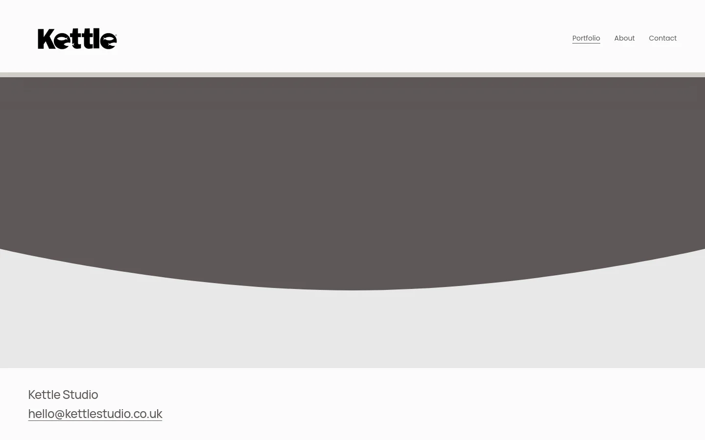 The Kettle Studio homepage features a minimalist design with a white header containing the logo and navigation links for Portfolio, About, and Contact. A large, dark grey curved hero section dominates the top, followed by a grid of portfolio projects showcasing high-end audio equipment and festival imagery. The footer contains the studio name and an email contact link against a light grey background.