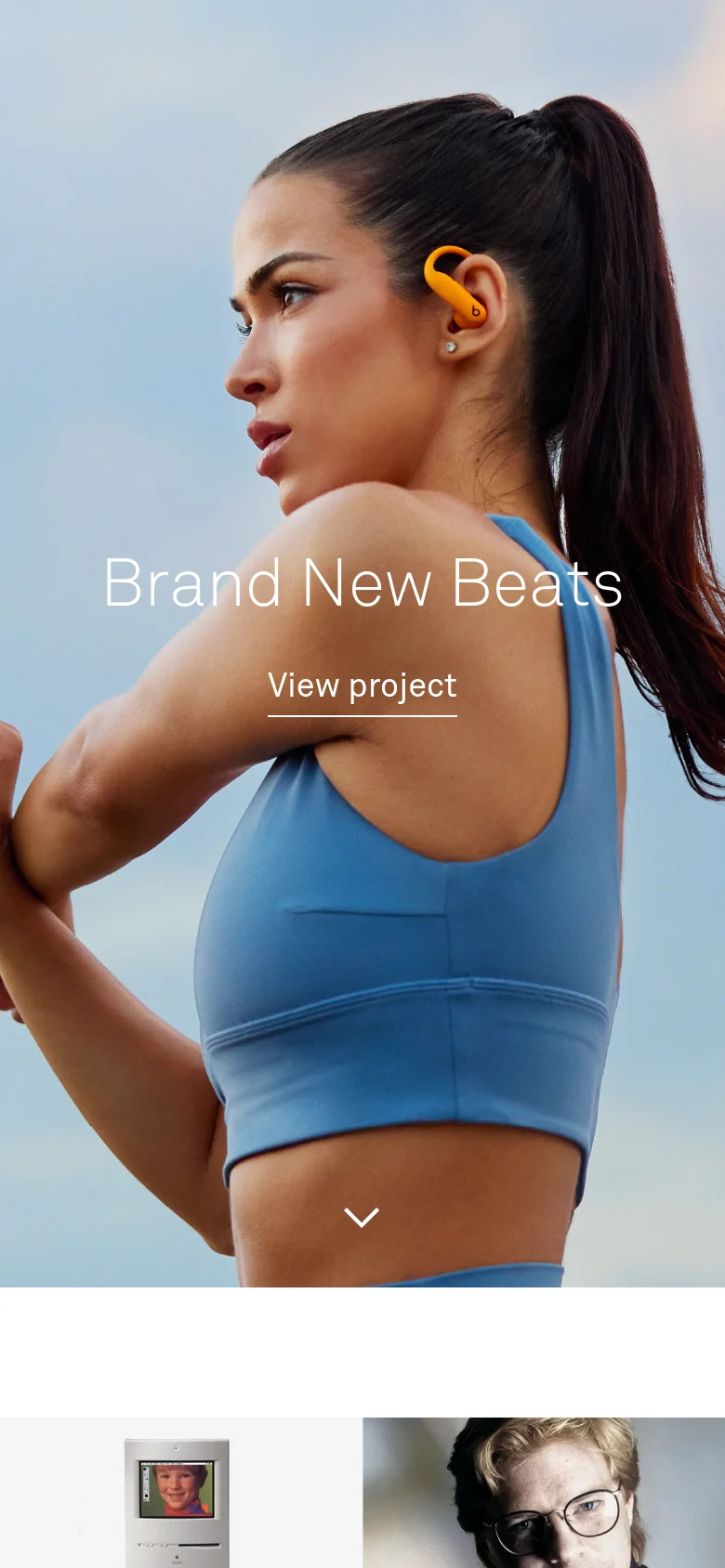 The mobile version presents a vertically oriented, full-screen hero image of the same woman wearing orange earbuds, emphasizing a portrait view. The 'Brand New Beats' headline and 'View project' link are stacked vertically in the center of the screen, and a downward arrow icon suggests scrolling for more content.