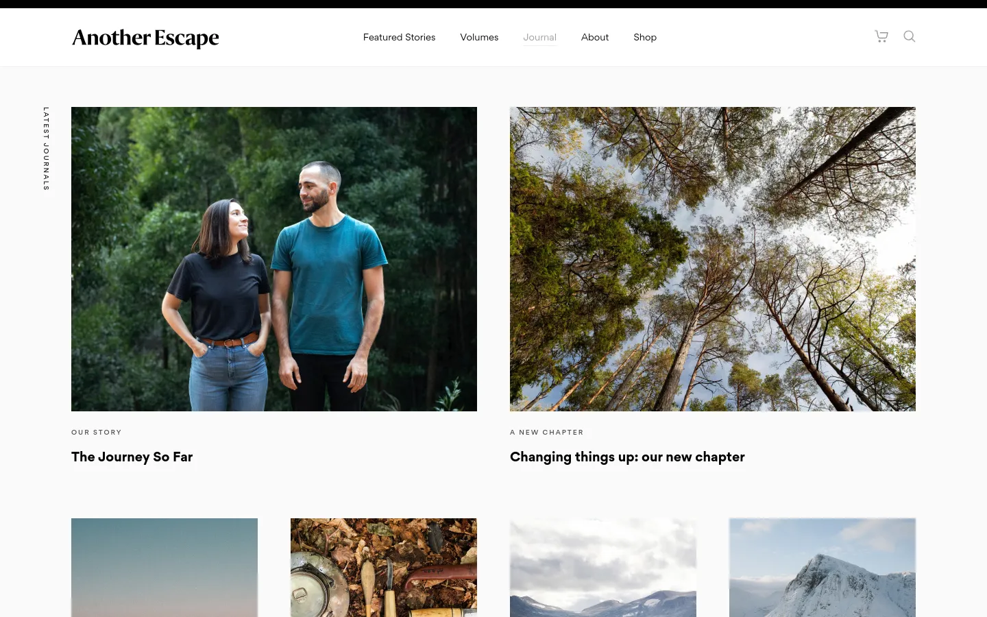 The Journal page features a clean, minimalist layout with a white background and black serif typography. A grid of large, high-quality nature and lifestyle images displays latest journal entries, each accompanied by a category label and a bold headline. The desktop navigation includes links for Featured Stories, Volumes, Journal, About, and Shop, alongside a shopping cart and search icon.