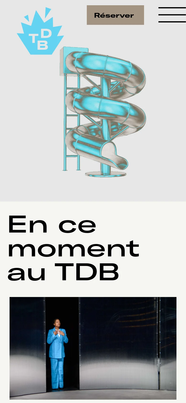 The mobile version presents a simplified vertical layout with a large TDB logo and a prominent 'Réserver' button centered above a large hamburger menu icon. Below the header, a large heading reads 'En ce moment au TDB' followed by a theatrical production image of a person in a blue suit standing in a doorway.