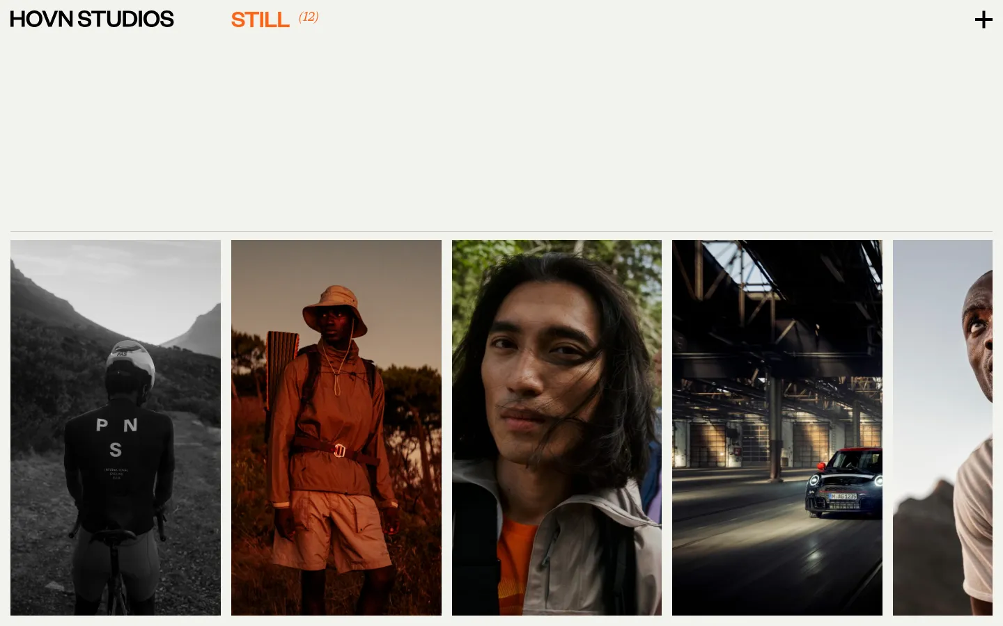 The desktop page features a minimalist white header with 'HOVN STUDIOS' and 'STILL (12)' in orange and black. Below, a large grid of vertical, cinematic lifestyle images showcases various outdoor and cycling campaigns with muted, earthy tones. The layout uses ample white space to separate the high-quality photography.