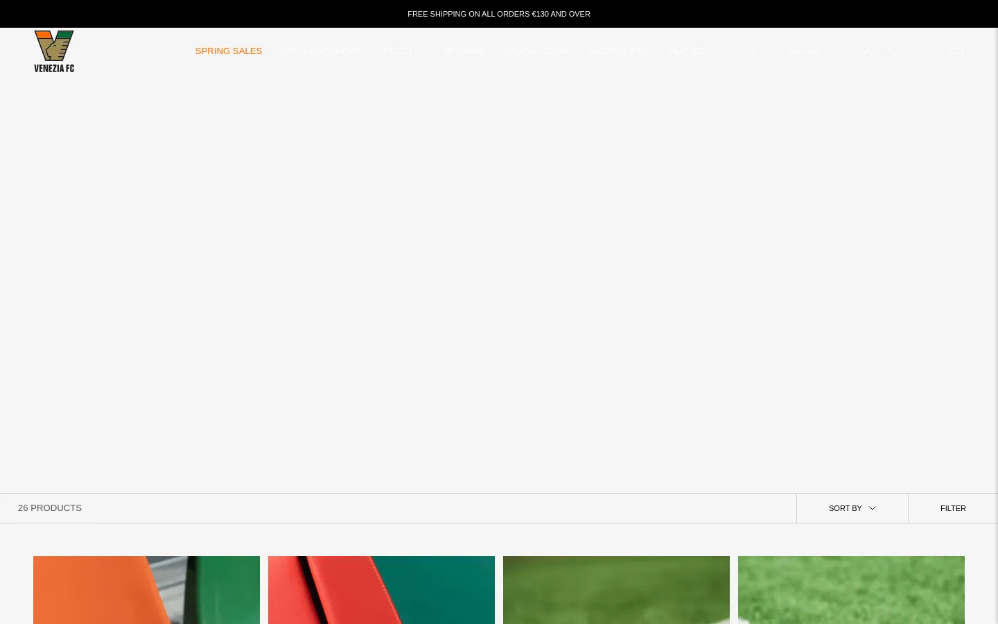 The desktop Accessories page features a large hero banner at the top, followed by a product grid displaying 26 items including New Era caps and scarves. A white navigation bar at the top includes the Venezia FC logo, menu categories like Spring Sales and Lifestyle, and utility icons. The layout uses a clean white background with black text and includes 'Filter' and 'Sort by' options above the product grid.