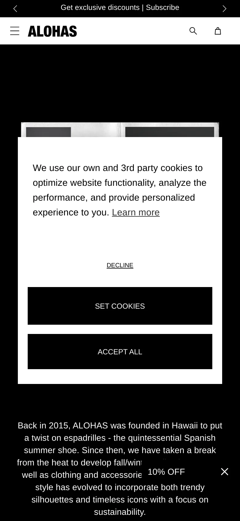 The mobile version presents a vertically stacked layout with the cookie consent modal occupying most of the screen. The hero imagery and text are scaled down, and the top navigation is condensed into a hamburger menu, logo, search icon, and shopping bag icon. A promotional banner for exclusive discounts appears at the bottom of the screen.