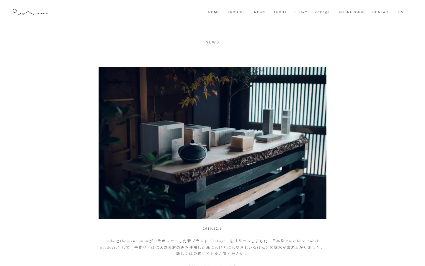 The News page features a minimalist white layout with a top navigation bar containing the Odai logo and links like HOME, PRODUCT, and NEWS. A large hero image shows various skincare products arranged on a rustic wooden table against a dark, atmospheric background. Below the image, a news entry dated 2019.12.1 describes the launch of the 'cokage' brand in Japanese text.