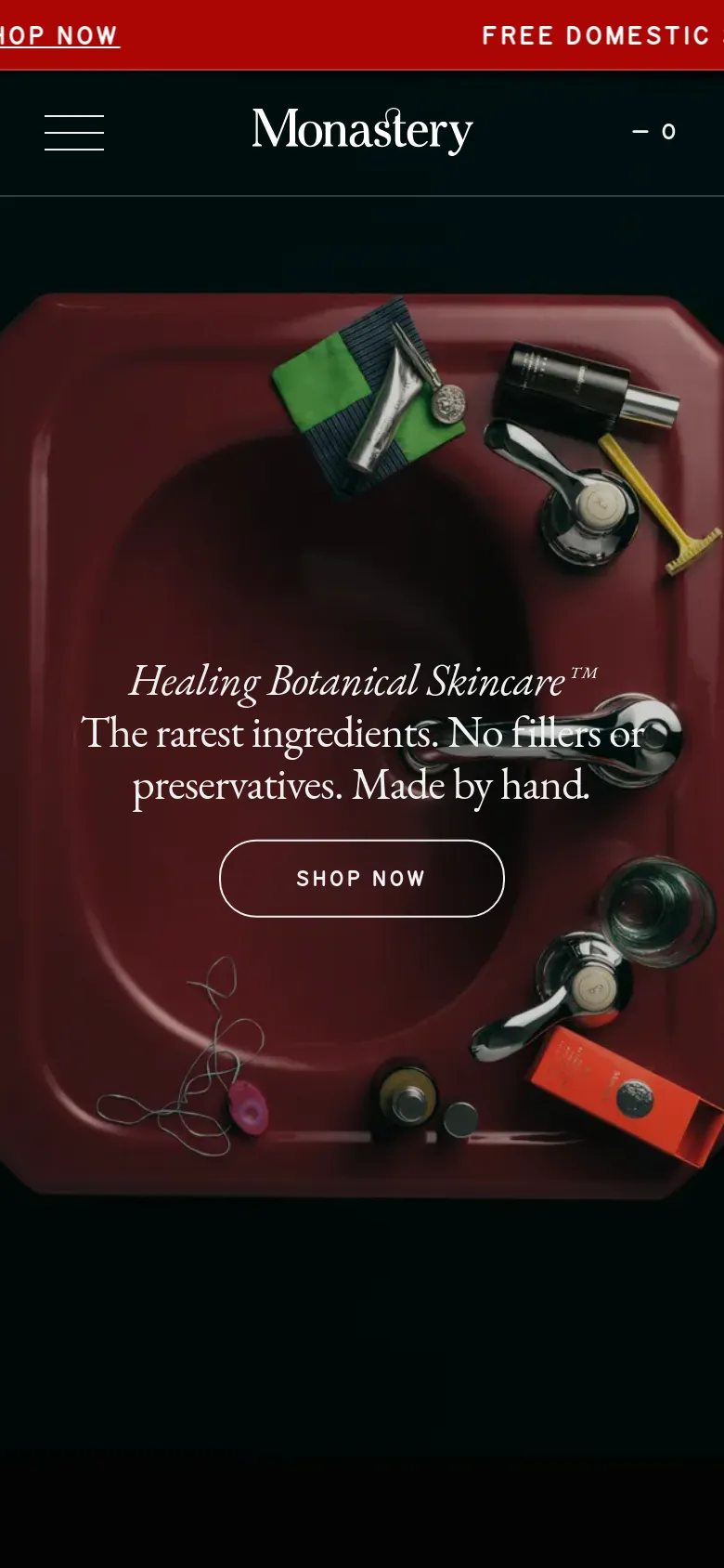 The mobile version presents a vertically stacked layout with a simplified navigation menu represented by a hamburger icon. The hero section features the same deep red sink imagery and central 'SHOP NOW' call to action, but the text is scaled for smaller screens and the top navigation links are tucked into a menu. A floating red button at the bottom right promotes 'THE AT HOME FACIAL'.