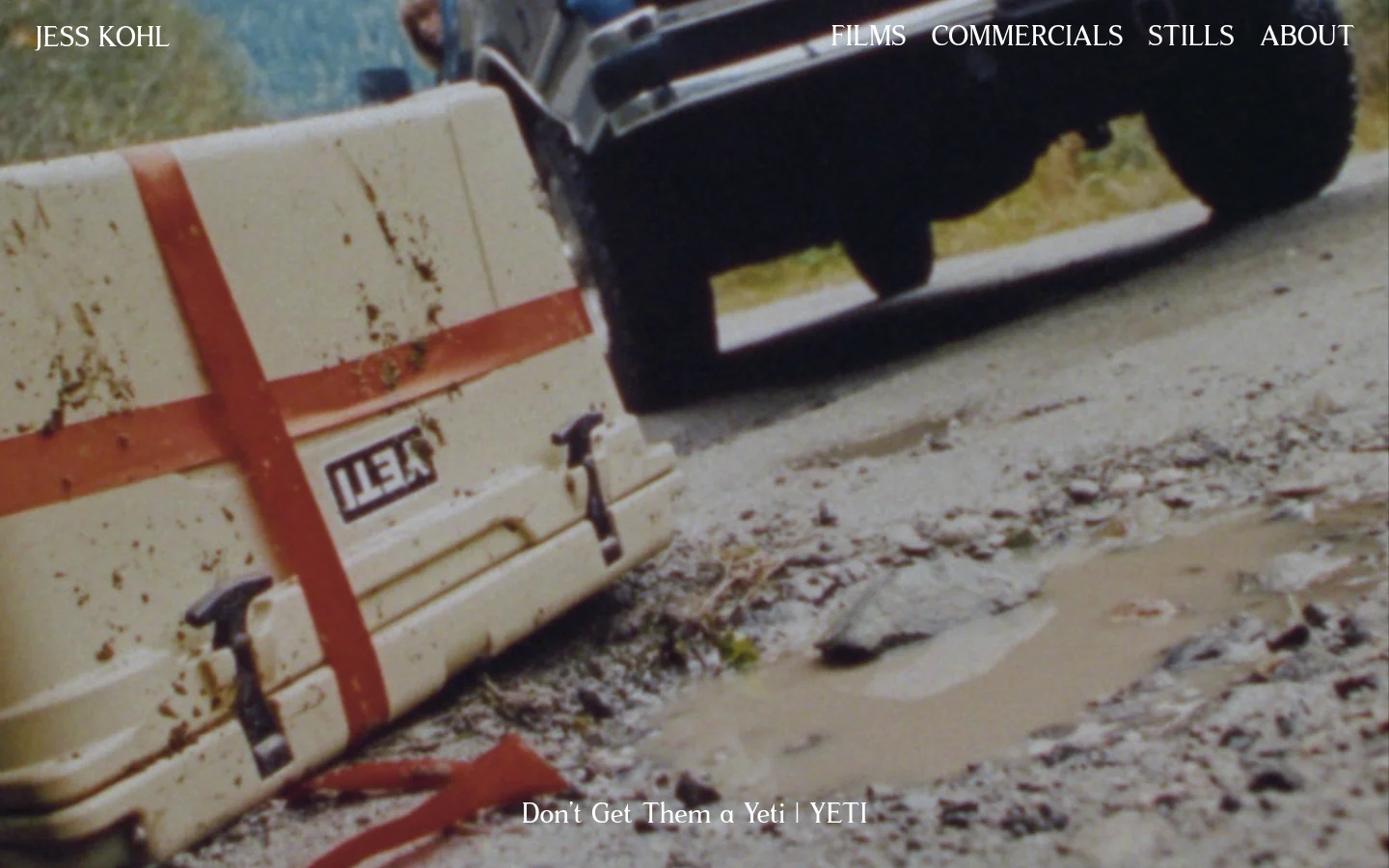 The desktop page features a minimalist white navigation menu at the top right and the name 'JESS KOHL' on the left. The main content is a large, cinematic hero image from a Yeti commercial showing a white cooler on a muddy road next to a vehicle, with the title 'Don’t Get Them a Yeti | YETI' overlaid at the bottom.