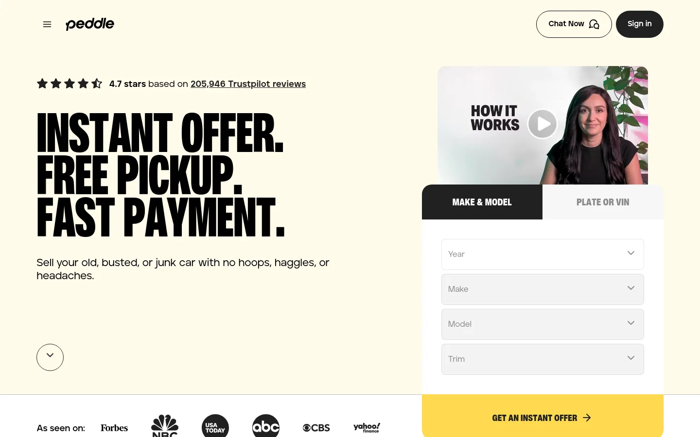 The desktop homepage features a clean white and yellow layout with a large, bold headline: 'INSTANT OFFER. FREE PICKUP. FAST PAYMENT.' To the right is a video thumbnail titled 'HOW IT WORKS' and a car valuation form with tabs for 'MAKE & MODEL' or 'PLATE OR VIN'. A prominent yellow 'GET AN INSTANT OFFER' button sits at the bottom of the form, and Trustpilot ratings and media logos are displayed below the hero section.