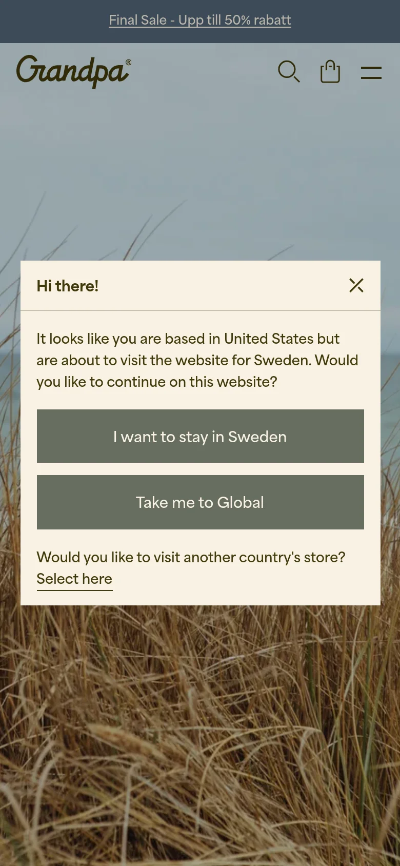 The mobile version simplifies the layout with a hamburger menu, search icon, and shopping bag icon in the header. The central location-selection modal remains prominent over the beach grass background, and the top sale banner is scaled for a smaller screen.