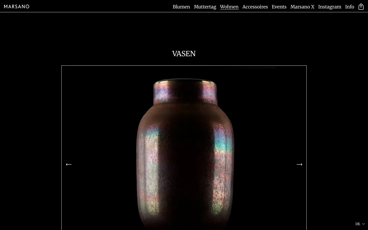 The desktop page features a minimalist black background with white serif text. A large hero section displays a close-up image of a dark, iridescent vase centered within a thin white frame, flanked by navigation arrows. The top navigation bar includes links for Blumen, Muttertag, Wohnen, Accessoires, Events, Marsano X, Instagram, and Info.