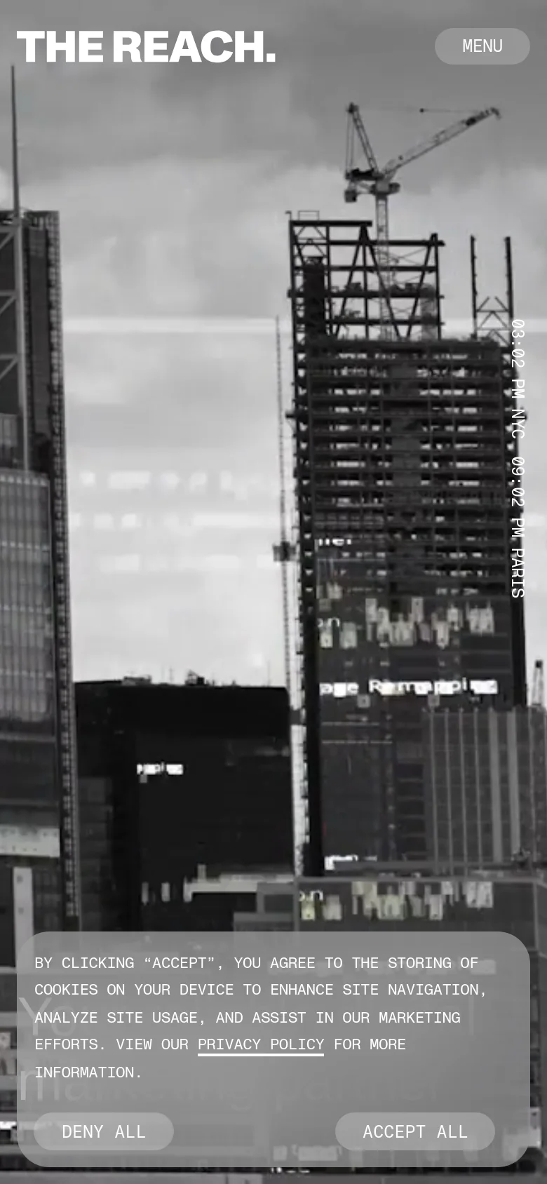 The mobile version presents a simplified layout with a large, black-and-white background image of city construction and skyscrapers. The 'THE REACH.' logo is prominent at the top left, paired with a 'MENU' button on the top right, and the cookie consent banner occupies the bottom portion of the screen.