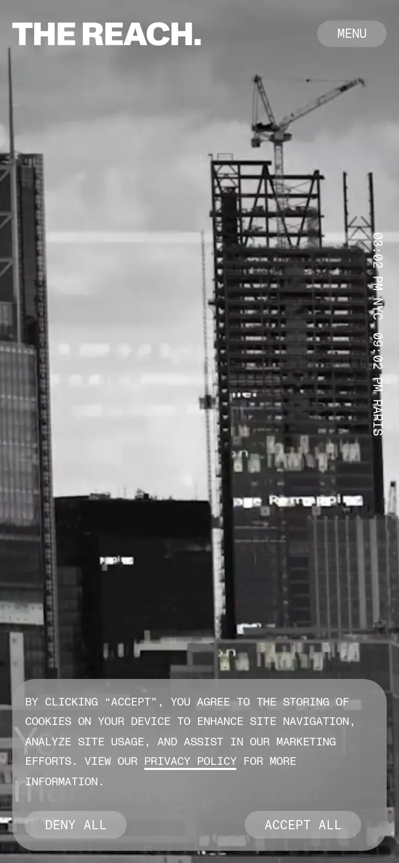 The mobile version presents a simplified layout with a large, black-and-white background image of city construction and skyscrapers. The 'THE REACH.' logo is prominent at the top left, paired with a 'MENU' button on the top right, and the cookie consent banner occupies the bottom portion of the screen.