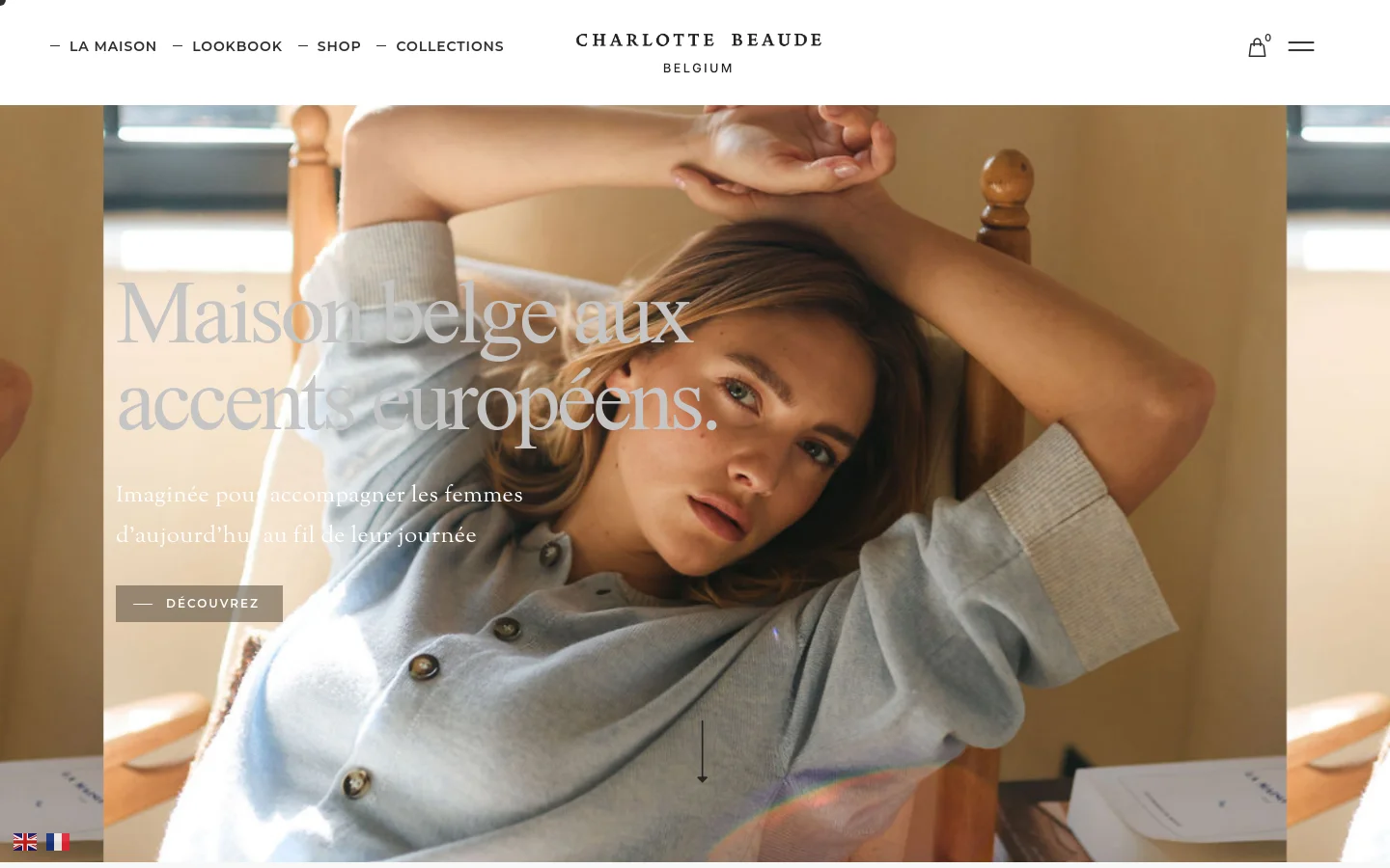 The desktop homepage features a minimalist design with a large hero image of a woman in a light blue cardigan sitting in a wooden chair. Overlaid white text reads 'Maison belge aux accents européens' with a 'Découvrez' call-to-action button. The navigation menu is at the top with links for La Maison, Lookbook, Shop, and Collections, alongside a shopping bag icon.