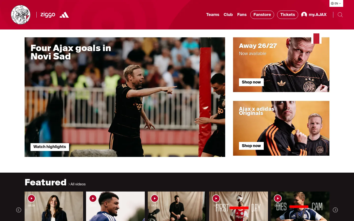 The Ajax homepage features a red and white header with navigation links and a search icon. The hero section displays a large image of a player celebrating with the headline 'Four Ajax goals in Novi Sad' and a 'Watch highlights' button, flanked by two rectangular promotional tiles for 'Away 26/27' and 'Ajax x adidas Originals' kits. Below, a 'Featured' video section shows a horizontal row of video thumbnails with play icons.