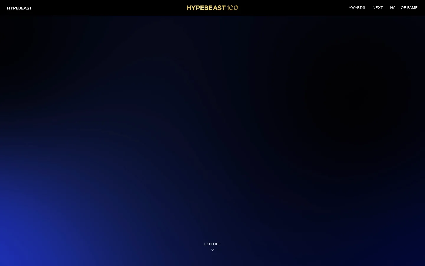 The Hypebeast100 desktop landing page features a dark, minimalist design with a deep blue to black gradient background. The top navigation bar includes the Hypebeast logo on the left, the Hypebeast100 logo in the center, and links for Awards, Next, and Hall of Fame on the right. A centered 'EXPLORE' call to action with a downward arrow sits at the bottom of the screen.