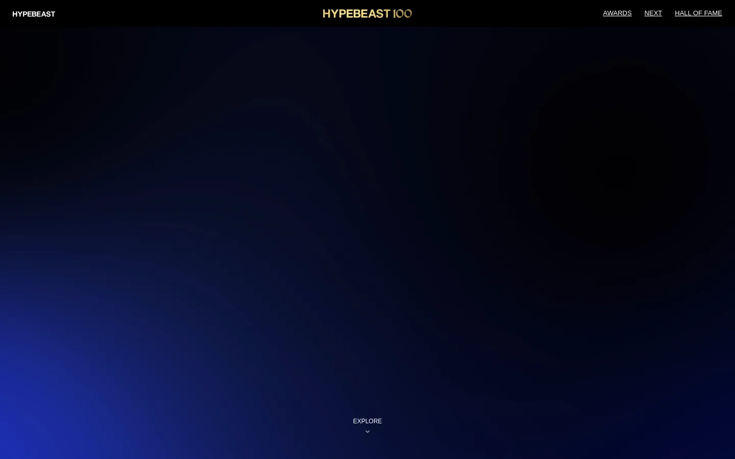 The Hypebeast100 desktop landing page features a dark, minimalist design with a deep blue to black gradient background. The top navigation bar includes the Hypebeast logo on the left, the Hypebeast100 logo in the center, and links for Awards, Next, and Hall of Fame on the right. A centered 'EXPLORE' call to action with a downward arrow sits at the bottom of the screen.