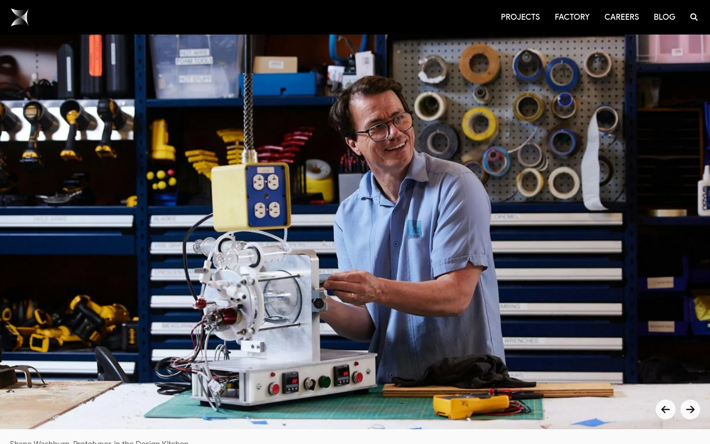 A desktop view of the Careers page featuring a large hero image of Shane Washburn, a Prototyper, working in a workshop filled with tools and supplies. Below the image, a large 'Careers' heading is followed by an introductory paragraph and a dropdown menu to filter job positions, starting with an 'Administrative' section.