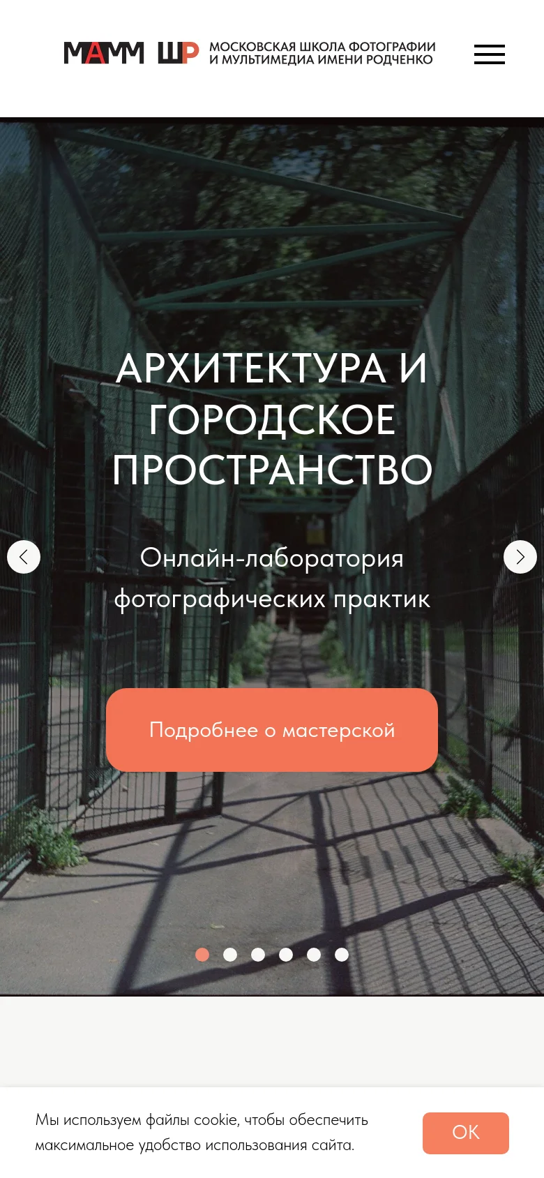 Mobile version of the homepage featuring a simplified header with the school logo and a hamburger menu icon. The hero section displays a full-width image slider with large white text overlaying an urban scene, a central orange call-to-action button, and navigation dots at the bottom. A cookie consent banner appears at the bottom of the screen.