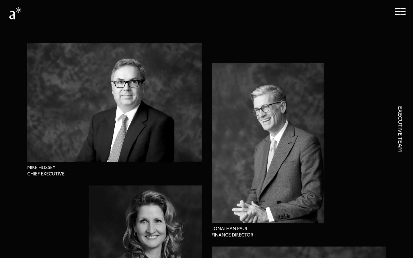 The desktop page features a dark, minimalist layout with black backgrounds and white text. Large, black-and-white portrait photographs of the executive team are arranged in an asymmetrical grid, with names and titles like 'Mike Hussey, Chief Executive' positioned next to the images. A vertical 'EXECUTIVE TEAM' label runs along the right edge of the screen.