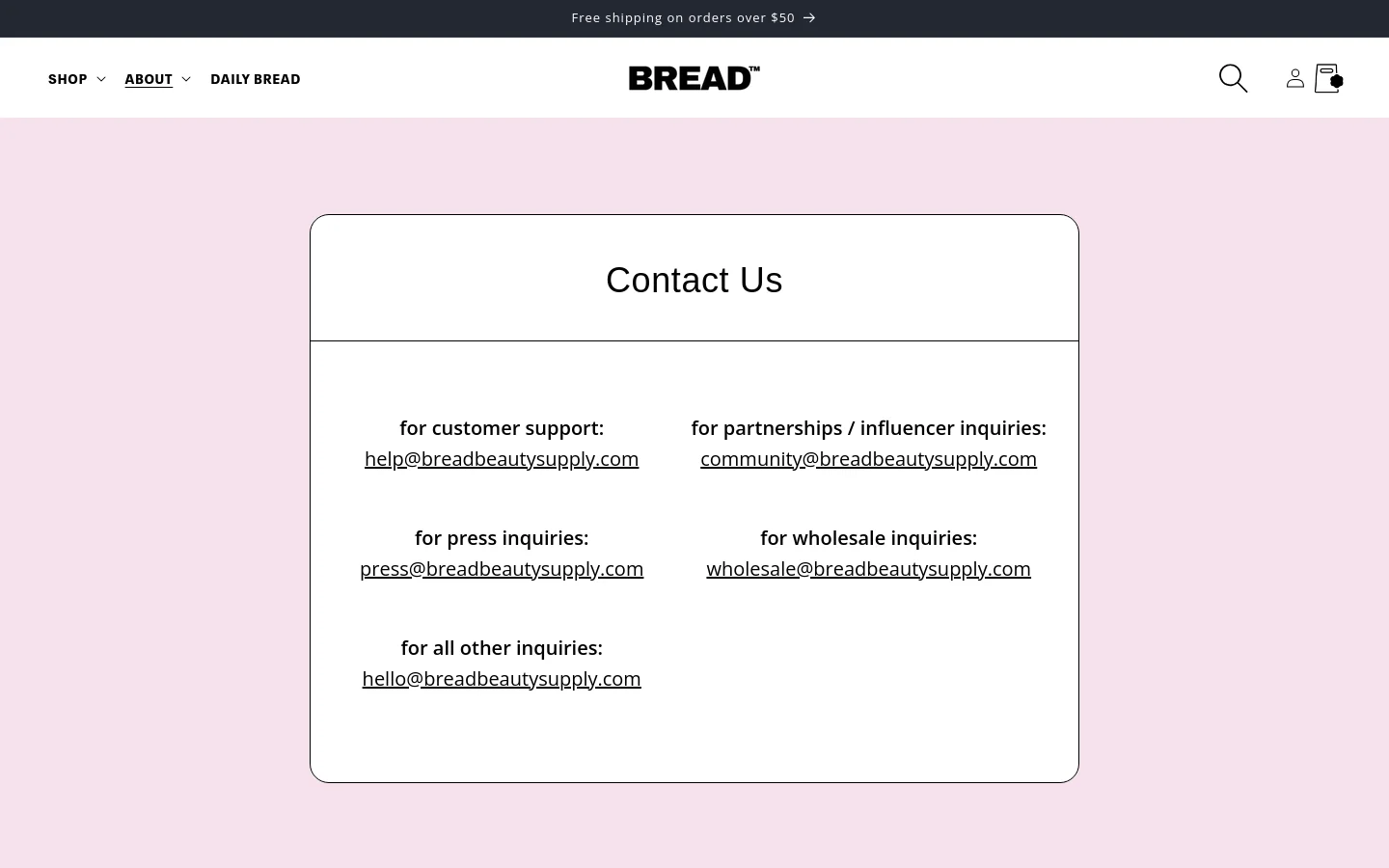 The desktop Contact Us page features a minimalist design with a light pink background and a large white central container. Inside the container, various contact email addresses are organized into two columns under bold headings for customer support, partnerships, press, wholesale, and general inquiries. The top navigation bar is white and includes the BREAD logo, shop and about dropdowns, a search icon, and a user account icon.