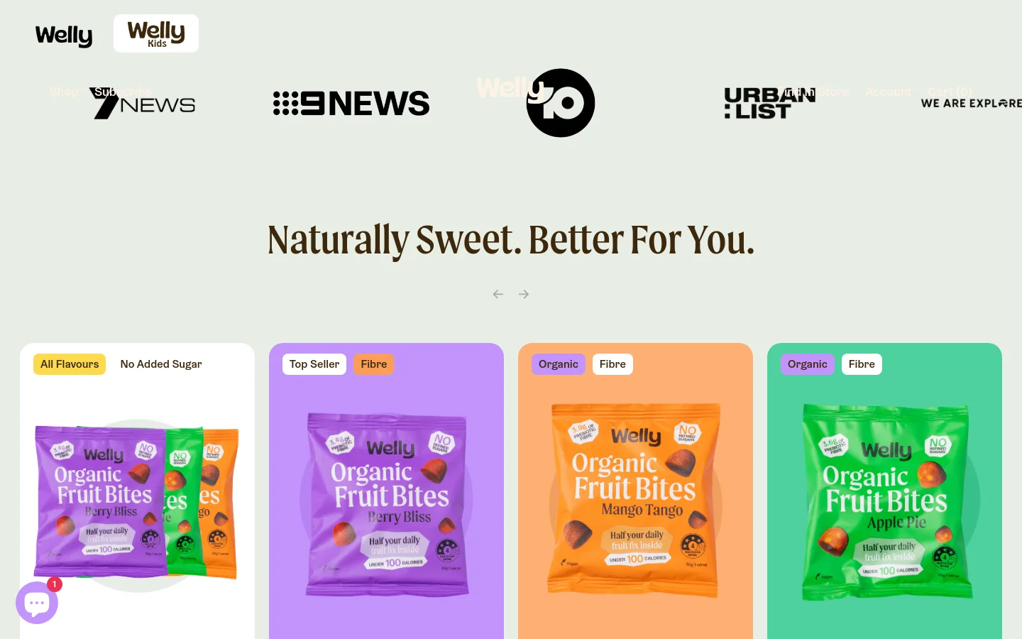 The desktop homepage features a light mint green background with a centered headline reading 'Naturally Sweet. Better For You.' Below the headline, a horizontal row of colorful product cards showcases Welly Organic Fruit Bites in various flavors like Berry Bliss and Mango Tango, each with labels like 'All Flavours' or 'Top Seller.' The navigation bar at the top includes the Welly and Welly Kids logos, shop links, and account options.