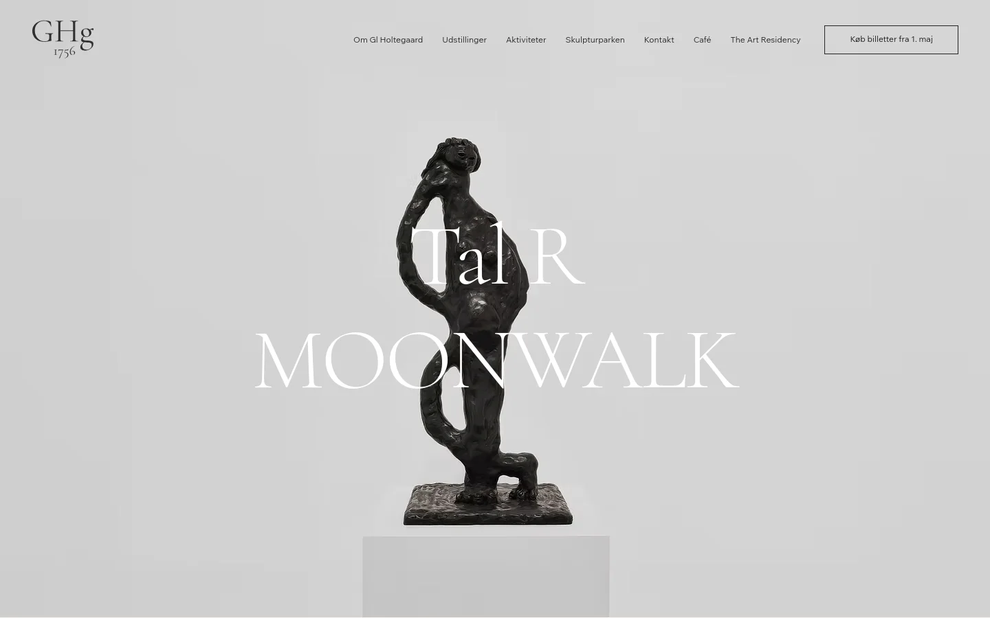 The desktop homepage features a minimalist light gray background with a large central hero image of a dark bronze sculpture titled 'Tal R MOONWALK'. A clean navigation menu at the top includes links like 'Om Gl Holtegaard' and 'Udstillinger', alongside a prominent 'Køb billetter fra 1. maj' call-to-action button. The layout is spacious and centered, emphasizing the artwork.