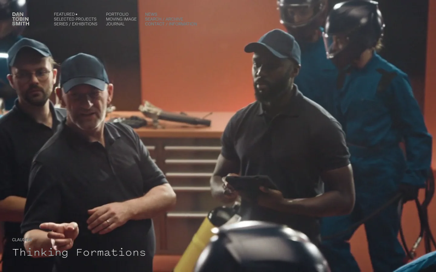 The desktop homepage features a large, cinematic hero image of several men in dark clothing and blue jumpsuits, with the headline 'Thinking Formations' in white text at the bottom left. The navigation menu is minimalist, located at the top with links for Featured, Portfolio, News, Selected Projects, Moving Image, Search / Archive, Series / Exhibitions, Contact, and Information. The color palette is dominated by dark, moody tones and warm orange backgrounds.