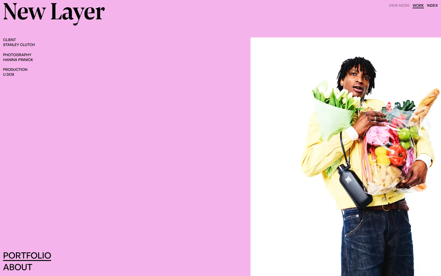 The desktop homepage features a minimalist pink background with the 'New Layer' logo in large black serif font on the left. A large hero image on the right shows a person in a yellow shirt holding groceries and flowers, accompanied by project details like client 'Stanley Clutch' and production credits. Navigation links for 'VIEW MODE', 'WORK', and 'INDEX' are located in the top right corner.