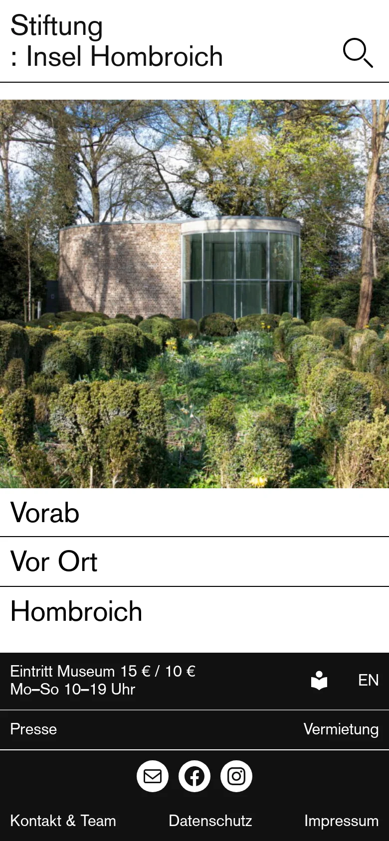 The mobile version presents a simplified vertical layout with the site title and a search icon at the top. The large hero image of the brick building and greenery is centered, followed by the main navigation links 'Vorab', 'Vor Ort', and 'Hombroich' stacked vertically as full-width bars. The footer is condensed, placing contact and legal links at the bottom below social media icons.