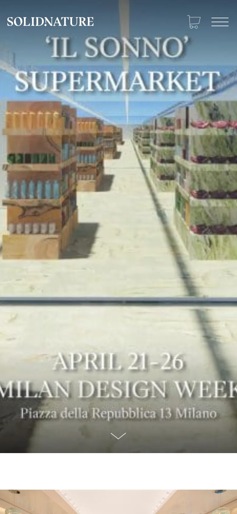 The mobile version presents a vertically oriented view of the same surreal marble supermarket hero image, with text centered to fit the narrow screen. The header is condensed, showing the SolidNature logo, a shopping cart, and a hamburger menu icon at the top. The overall aesthetic remains high-end and minimalist, emphasizing large-scale visual impact.