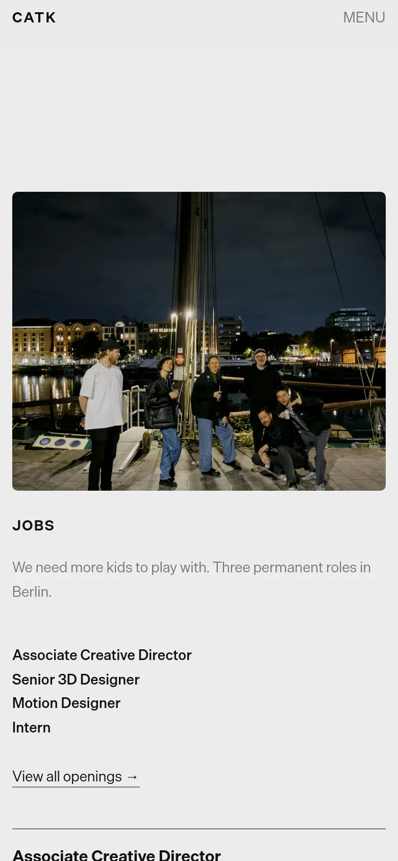 The mobile version presents a vertically stacked layout starting with a full-width hero image of four people outdoors at dusk. The 'JOBS' heading and job list follow below, optimized for vertical scrolling, with the navigation condensed into a 'MENU' button at the top right.