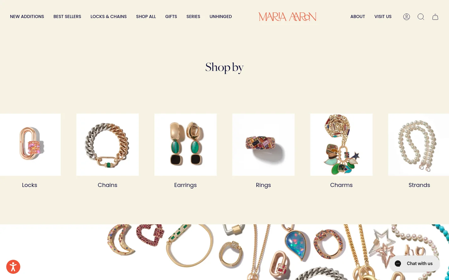 The desktop homepage features a minimalist cream background with a centered 'Shop by' heading. Below, a horizontal row of six square product images showcases jewelry categories including Locks, Chains, Earrings, Rings, Charms, and Strands. A large hero banner at the bottom displays an array of gold and gemstone jewelry pieces scattered across the frame.