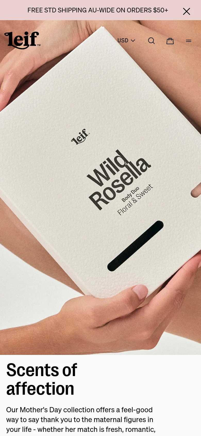 The mobile version presents a vertically stacked layout, beginning with a large hero image of the 'Wild Rosella' product box. The 'Scents of affection' headline and Mother's Day collection description follow directly below the image. The top navigation is condensed into a hamburger menu icon, with the brand logo, currency selector, search, and shopping bag icons arranged horizontally.