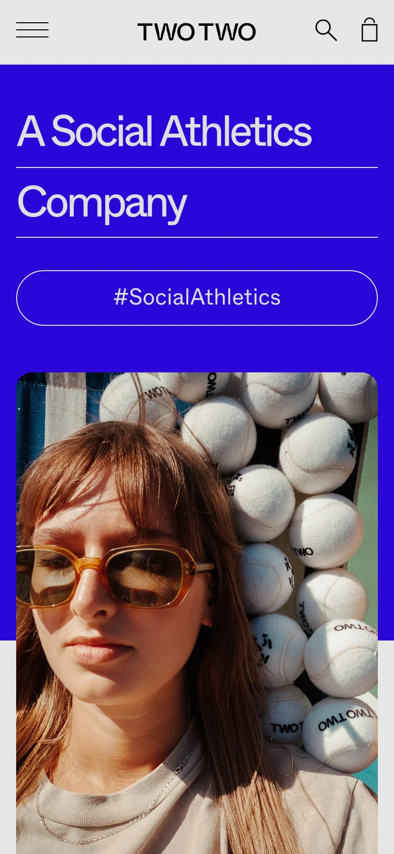 The mobile version presents a vertically stacked layout on a bright blue background. The headline 'A Social Athletics Company' is prominently displayed at the top, followed by a large, full-width button for '#SocialAthletics'. A lifestyle image of a person with sunglasses and sports balls occupies the bottom half of the screen.