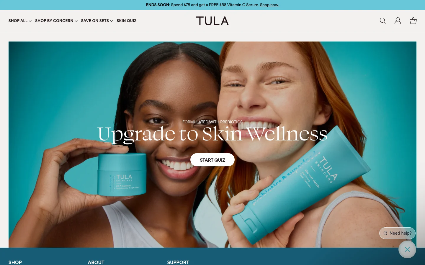 The desktop page features a large hero image of two smiling women holding TULA skincare products against a bright teal background. Centered white text reads 'Upgrade to Skin Wellness' above a white 'START QUIZ' button. The navigation bar at the top includes links for shopping categories and a search icon, set against a clean white header.