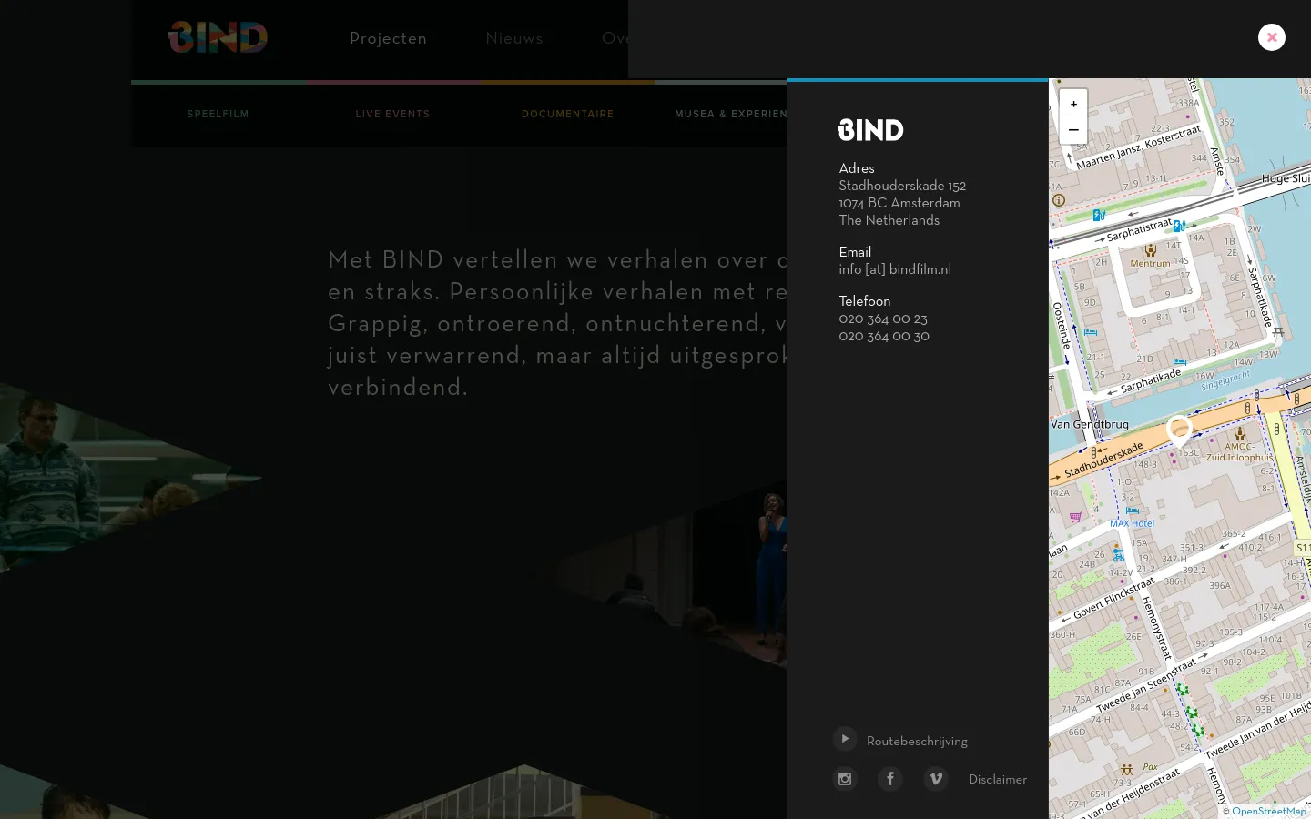 The desktop contact page features a dark, minimalist layout with a large map on the right side and contact details on the left. A large 'BIND' logo sits above the address, email, and phone number information, which is set against a dark background with subtle architectural imagery. The navigation menu is visible at the top, and a 'Routebeschrijving' button is located at the bottom left.