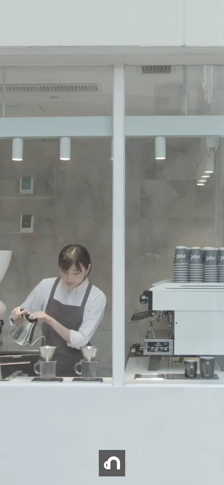 The mobile version presents a full-width, immersive view of the cafe interior through a window, focusing on a barista working. The navigation menu and logo are removed from the immediate view to prioritize the large-scale lifestyle imagery, creating a more streamlined and visual-centric experience.