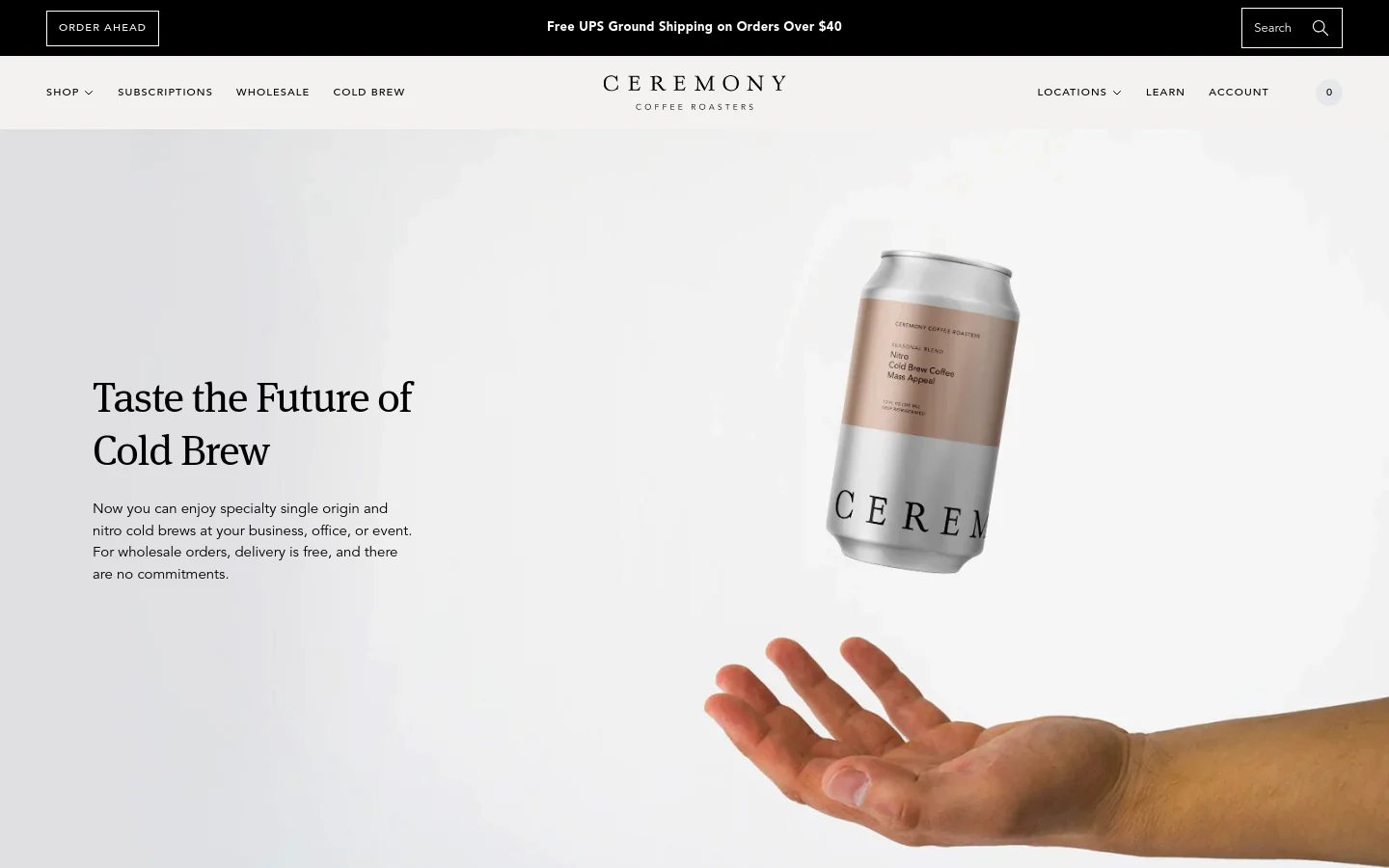 Desktop view of the Cold Brew page featuring a large hero image of a hand holding a silver Ceremony cold brew can against a light background. The headline 'Taste the Future of Cold Brew' is positioned to the left of the can, followed by a brief description of wholesale and single-origin options. The navigation bar at the top includes links for Shop, Subscriptions, Wholesale, and Cold Brew, alongside the Ceremony Coffee Roasters logo.