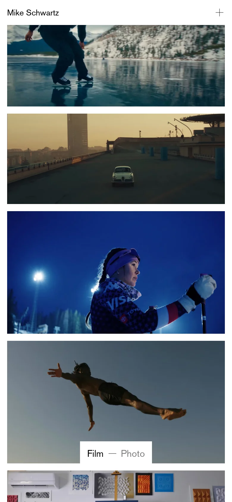 The mobile version maintains the minimalist aesthetic but transitions to a single-column vertical layout for the video thumbnails to fit the narrow screen. The navigation menu is condensed, featuring a plus icon for menu access next to the name 'Mike Schwartz'. The dominant colors remain the natural tones of the film stills against a clean white background.